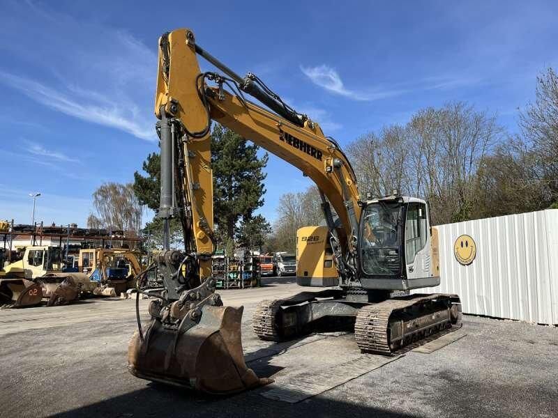 2015 Liebherr R 926 crawler excavator with a worn toothed digging bucket in the foreground and glazed white cab behind
