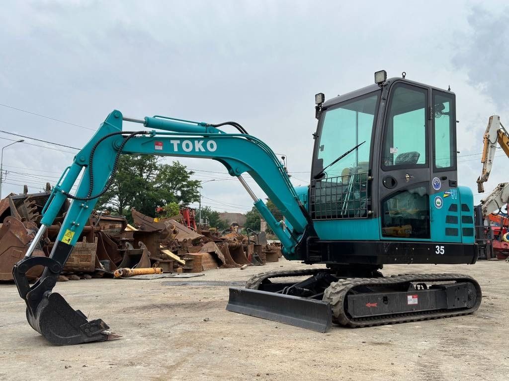 2022 Toko 35 Mini Excavator with teal body, black tracks, and a front view of the dozer blade and bucket. 2022 Toko 35 Mini Excavator with teal body, black tracks, and a front view of the dozer blade and bucket.