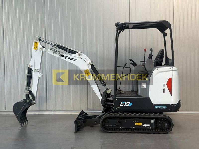 2025 Bobcat E19 Mini Excavator with its white boom and arm extended forward, featuring a digging bucket. 2025 Bobcat E19 Mini Excavator with its white boom and arm extended forward, featuring a digging bucket.